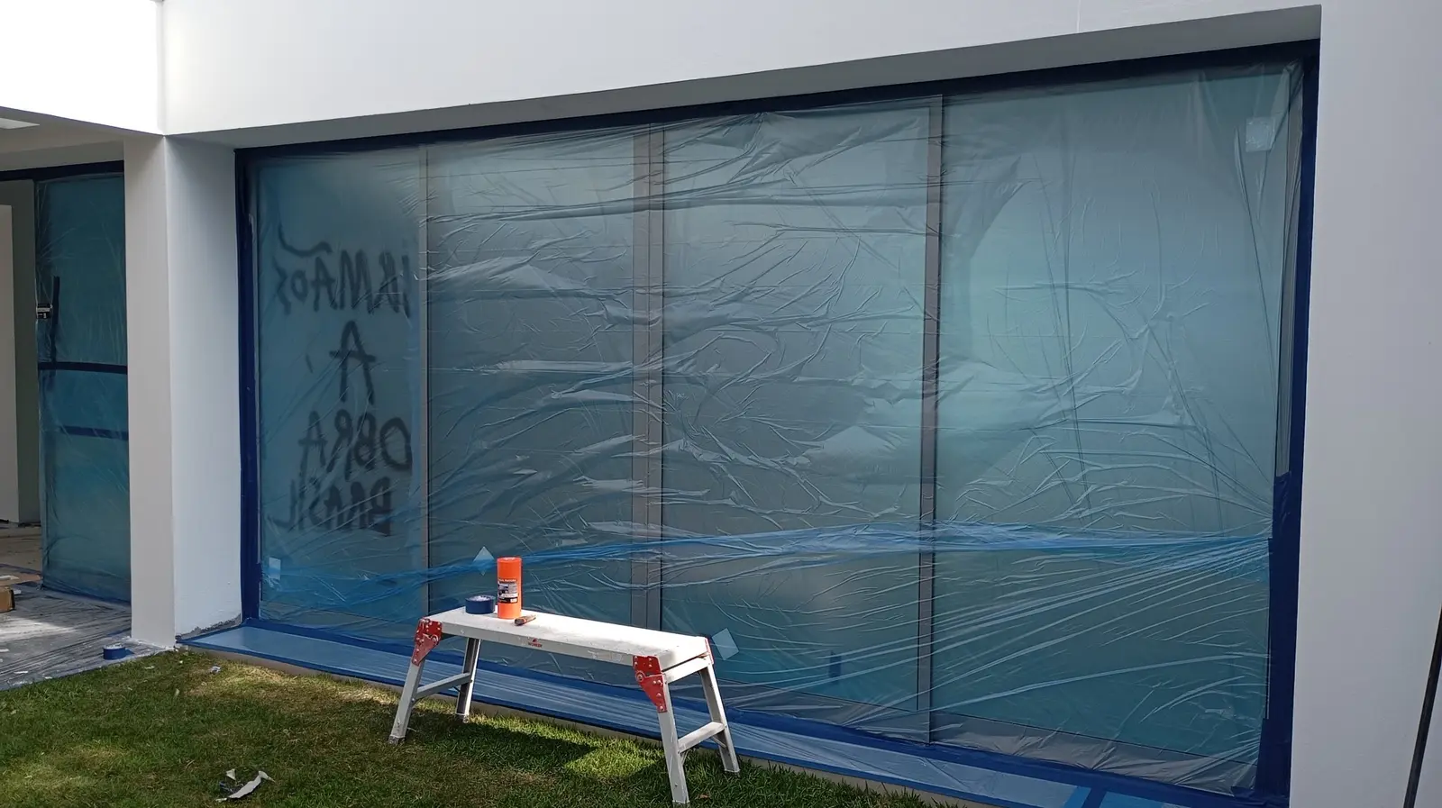 Portas de vidro e esquadrias protegidas com plástico e fita durante a pintura